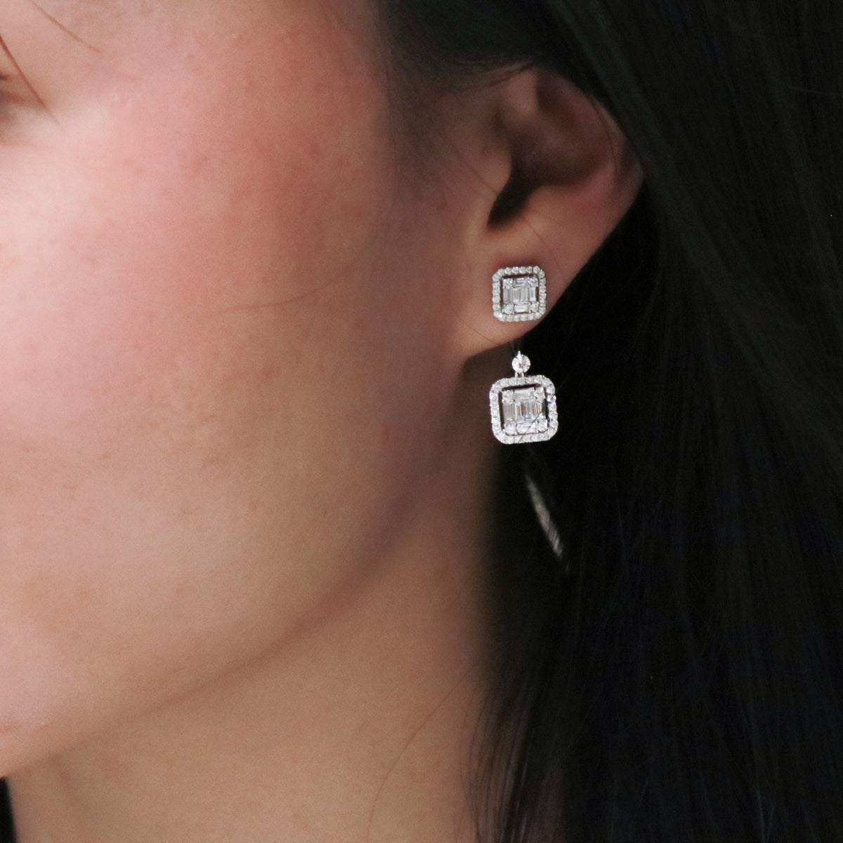 White gold cluster style diamond earrings with a dangling floating backing on a model.